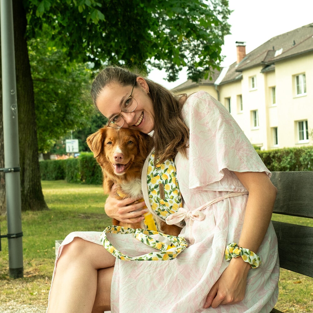 Ich (Kathi) lache in die Kamera und knie am Boden in einer wunderschönen Schneelandschaft. Meine Hündin ist neben mir und gibt mir eine Kuss auf die Backe.