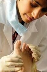 Een vrouwelijke zorgverlener die een voet onderzoekt