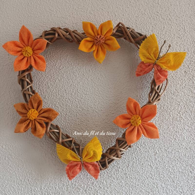 Papillons et fleurs en tissu sur coeur tressé.