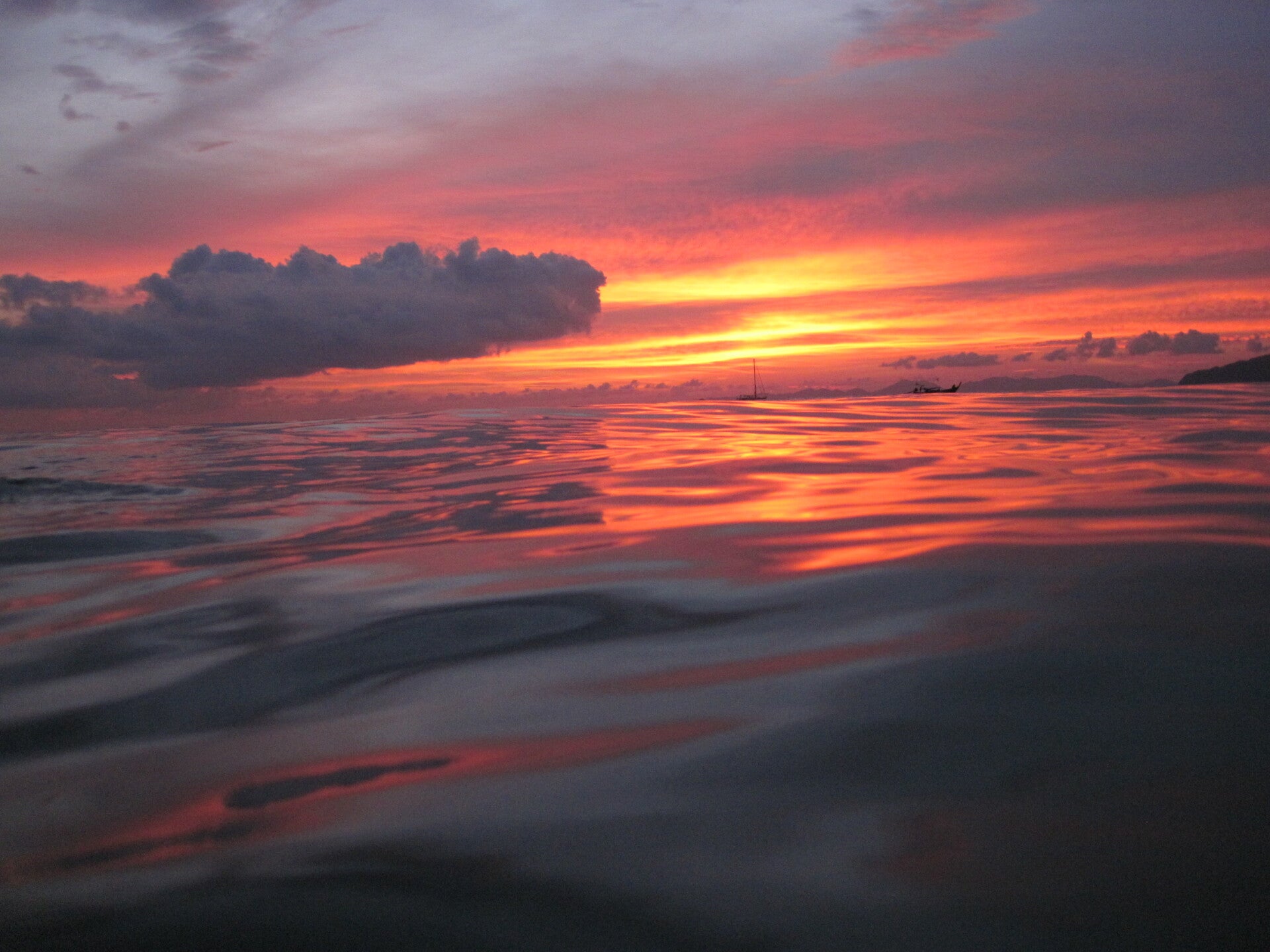 Sunset  across an ocean with a boat in the background.