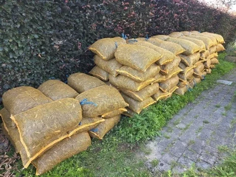 Zakken boomschors gestapeld langs een pad