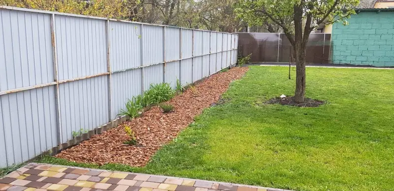 Boomschors aangebracht langs een tuinafscheiding als onderhoudsvriendelijke bodembedekking