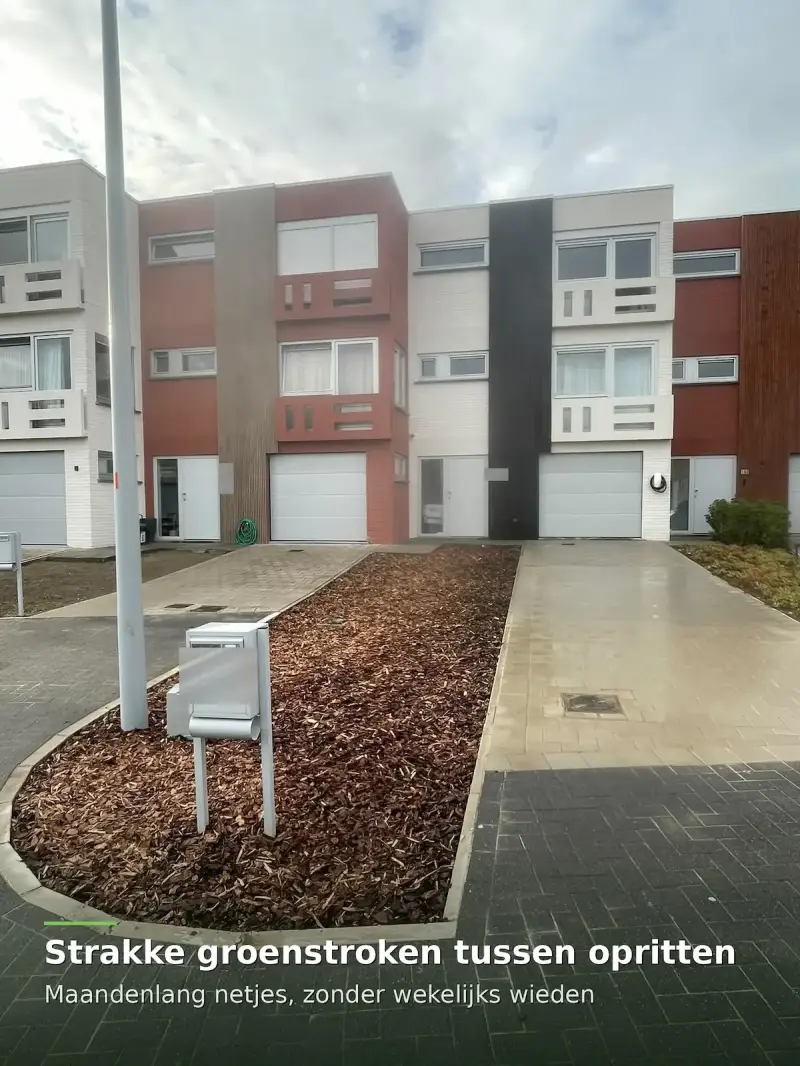 Groenstrook met boomschors tussen twee opritten voor een woning