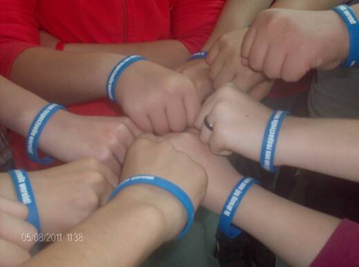 Leerlingen dragen blauwe respectbandjes met de boodschap ‘Ik draag bij aan een respectvolle wereld’ tijdens een gezamenlijke activiteit op school.