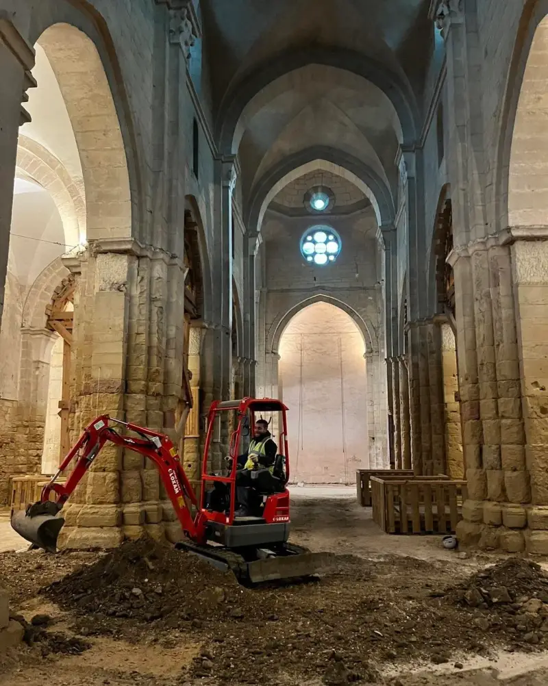 Travaux de terrassement et d’excavation dans la nef d’une église en pierre.