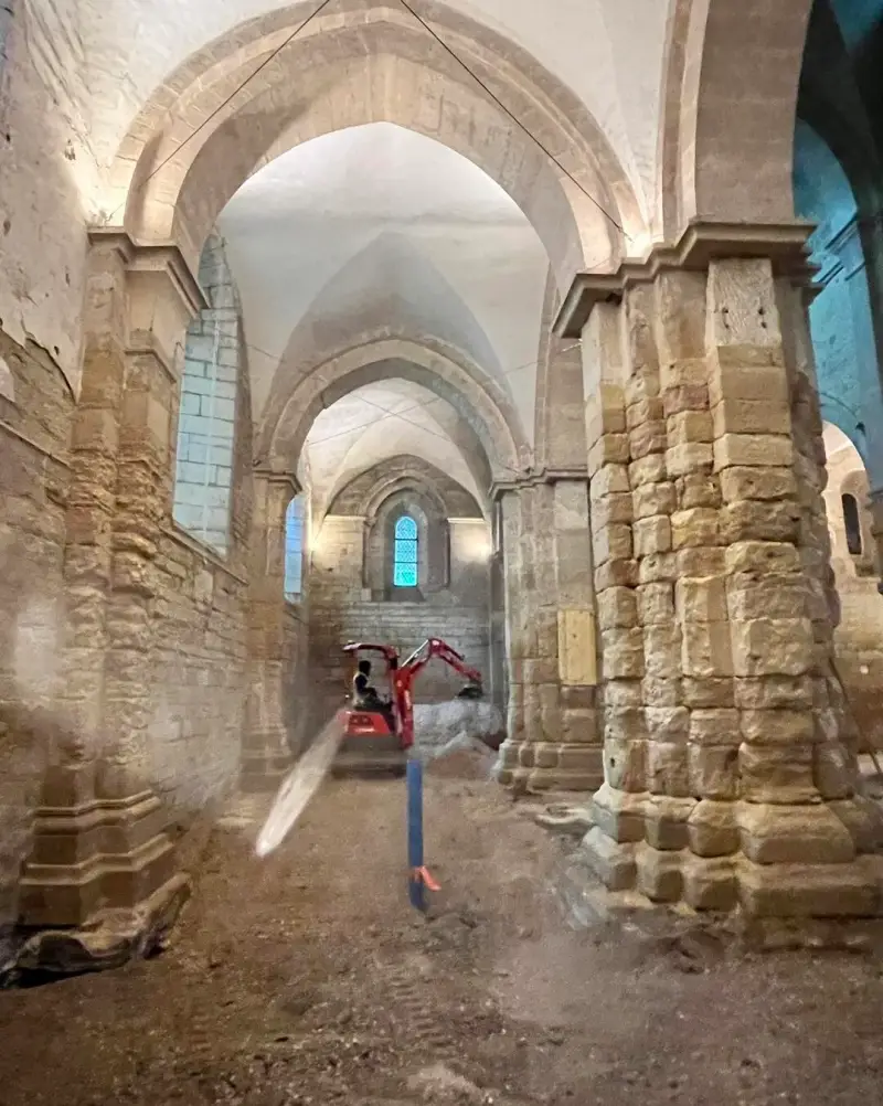 Mini-pelle en intervention lors de travaux de fouilles dans la nef d’une église historique.