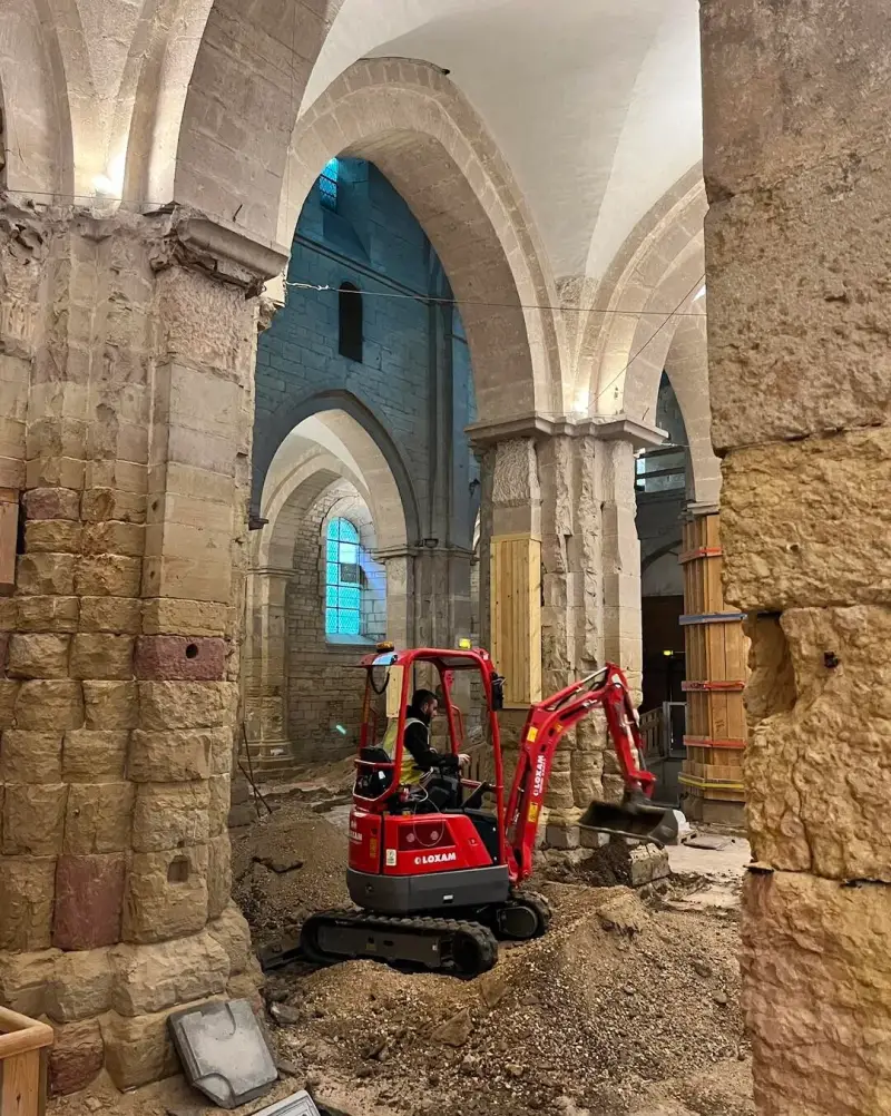 Mini-pelle utilisée pour des travaux de fouilles à l’intérieur d’un bâtiment religieux ancien.