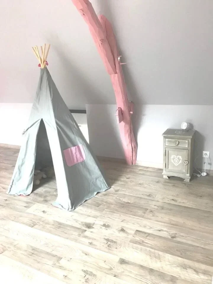 Espace de jeux aménagé sous les combles à Demigny avec parquet clair et poutre apparente peinte.