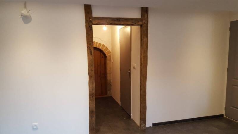 Détail d'un aménagement intérieur à Corgoloin avec ouverture habillée de poutres bois et finitions soignées après travaux.
