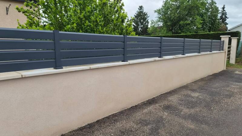 Muret de clôture rénové à Saint-Bernard après application d'un enduit beige sous une clôture aluminium gris anthracite.