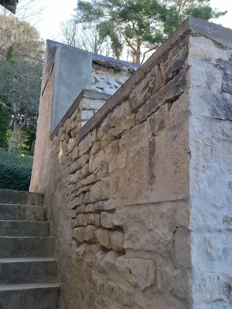 Travaux de maçonnerie traditionnelle sur un mur en pierre ancien à Ségrois.