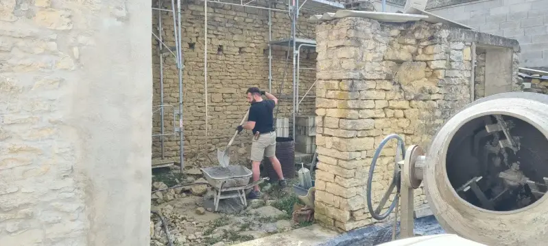 Chantier de rénovation d’un mur en pierre à Ségrois avec préparation du mortier.