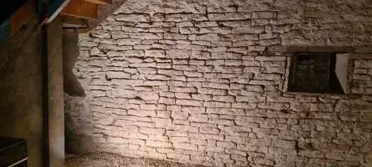 Mur en pierre apparent rénové à Saint-Bernard après nettoyage et remise en valeur des pierres anciennes.