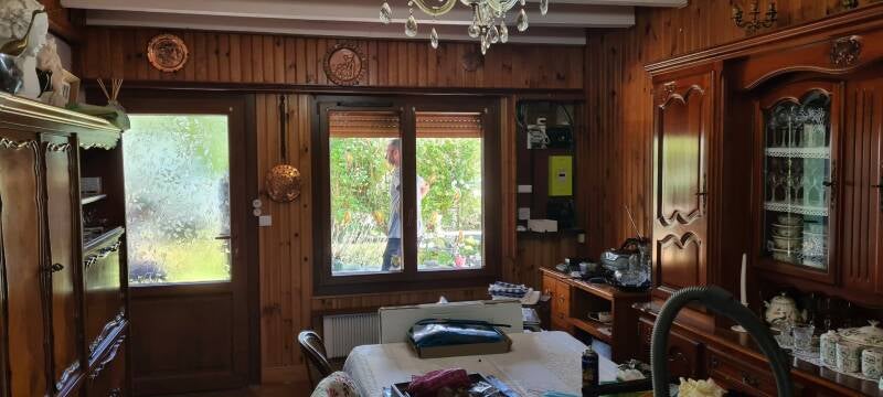 Avant travaux à Saint-Bernard : pièce de vie à rénover avec papier peint à rayures, lambris bois et aménagement ancien.