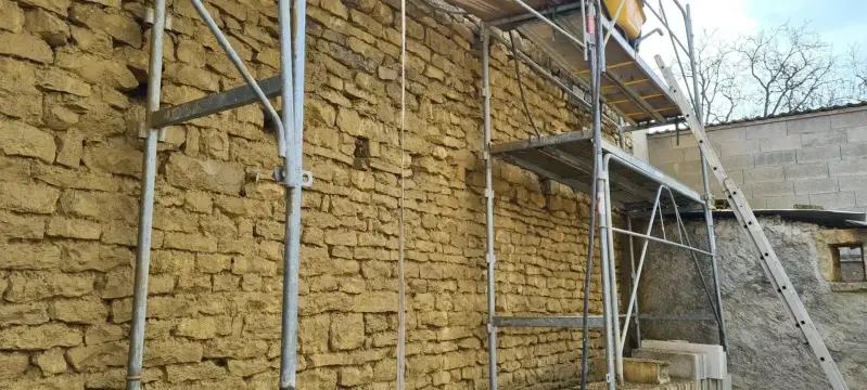 Rénovation d’un mur en pierre à Ségrois avec échafaudage et reprise de la maçonnerie ancienne.