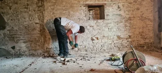 Rénovation d’un mur en pierre à Saint-Bernard : piquage et préparation du mur avant remise en valeur des pierres.
