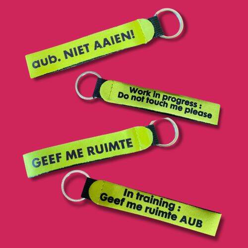 Gele honden lintjes met verschillende teksten: aub niet aaien, geef me ruimte, work in progress do not touch me please, in training geef me ruimte aub