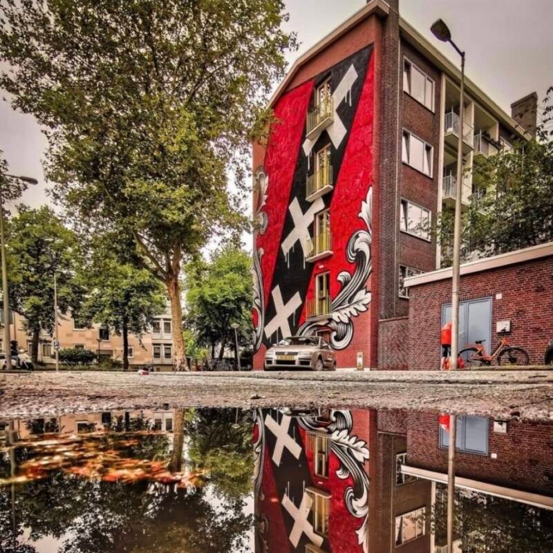 A massive modern mural on an urban wall featuring three stylized crosses, blending contemporary art with historical symbolism.
