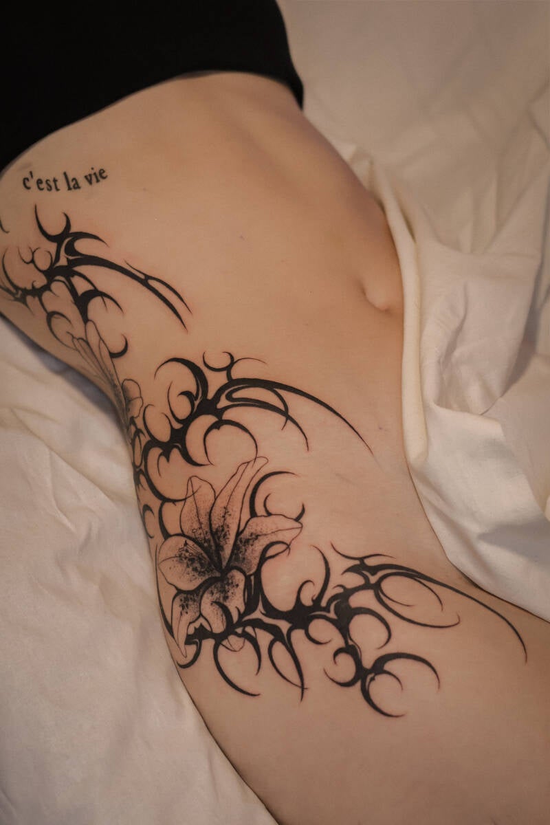Lilien Tribal blackworktattoo Hüfte Bauch bei einer Frau