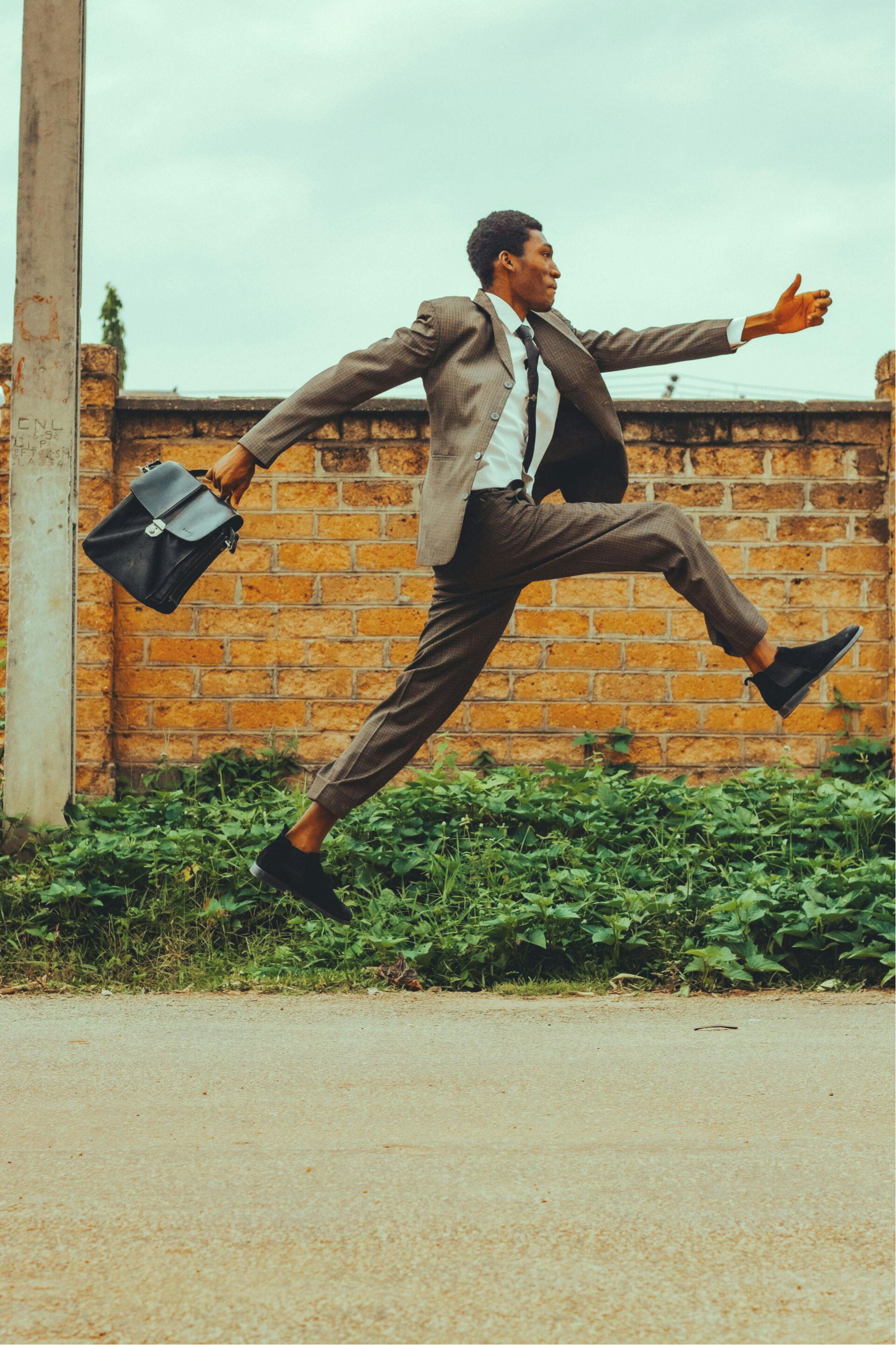 Man in pak met werktas die dansend marcheert met zwierige en heel grote passen.