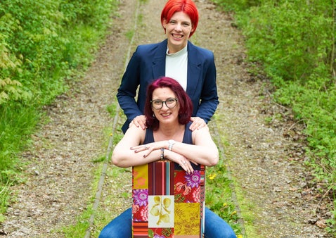 Stephanie Breschniak steht hinter einer Klientin im Grünen und haltet die Hände stärkend auf die Schultern der Sitzenden.