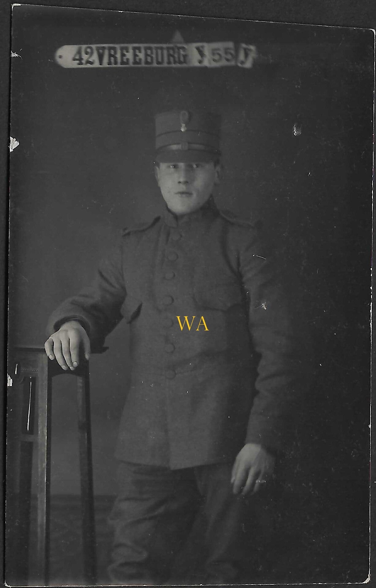 Small studio portrait of a Dutch soldier with the text “Vreeburg” in the background.