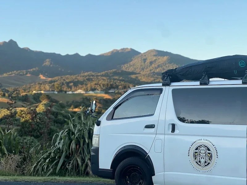 Cecily and partner smiling inside the Demeter campervan during their New Zealand road trip