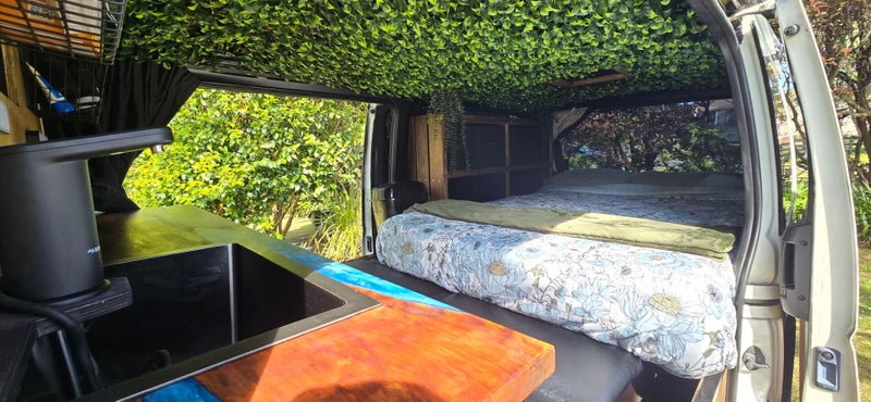 Interior view of the Demeter campervan showing the custom wooden build, sink, and cozy living space