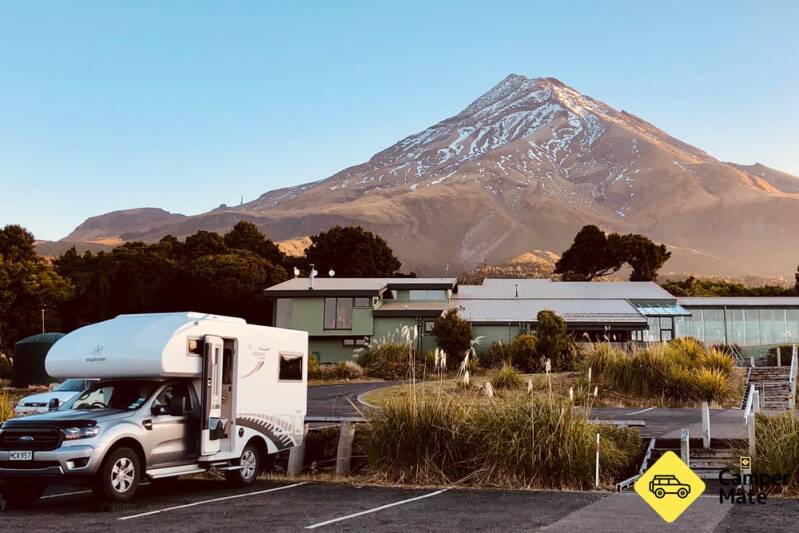 Freedpm Camping sight foudn in front of mount taranaki. the sky is clear and blue inviting travellers to wish to partake in such a walk with a beautiful area to freedom camp after a long days treck