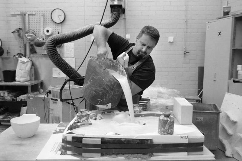 scupltor pours plaster in to mold, finland, an example of documentary photography, as sen in photo magazine Humanity,