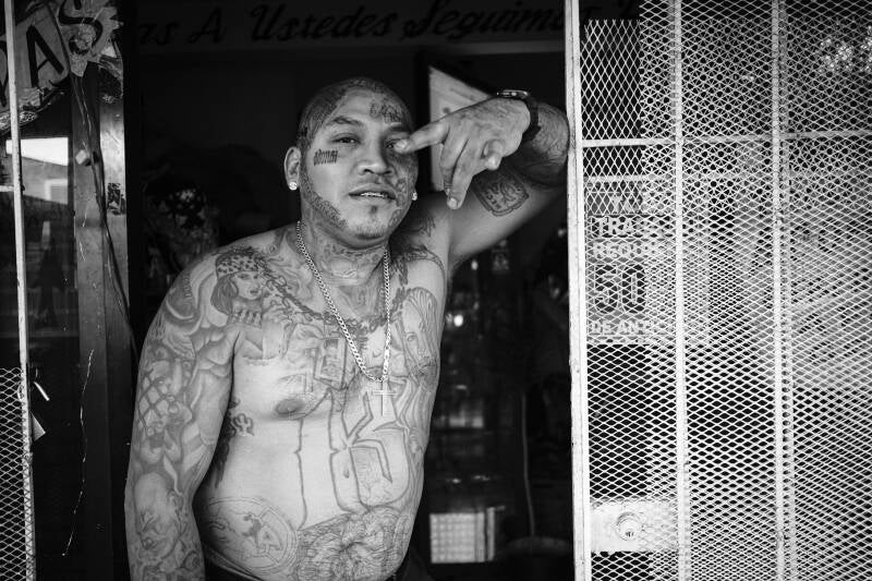 a tatooed gang menber photographed by Brice Gelot, whose documentary practice explores who gets photographed and why,
