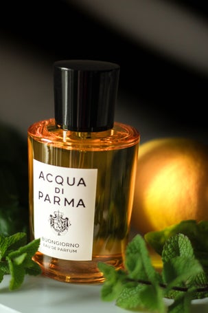 Perfume bottle styled with garden-fresh herbs and lemon