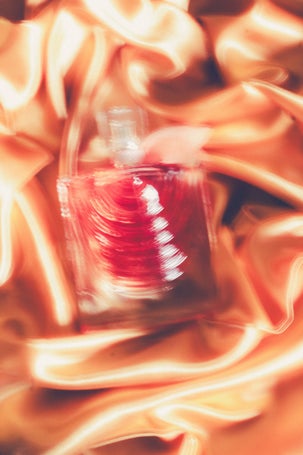 Artistic motion-blur photo of La Vie Est Belle Iris Absolu by Lancôme on golden satin fabric, capturing a dreamy and luxurious aesthetic.
