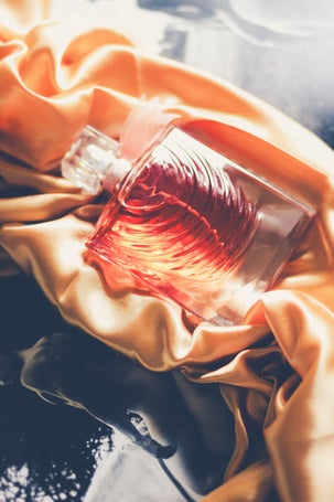 Artistic flat lay of Lancome’s La Vie Est Belle Iris Absolu with satin and photography
