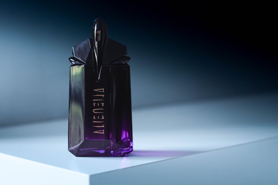 Mugler Alien Extraintense perfume lying on gradient background in a dramatic light