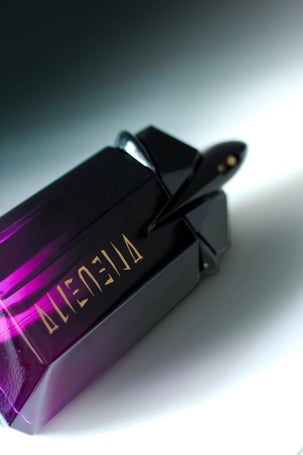 Close-up of Alien Extraintense bottle by Mugler with black-purple glass and gold logo
