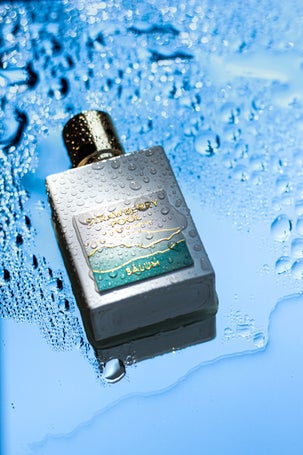 Perfume bottle laying horizontally on a reflective wet surface