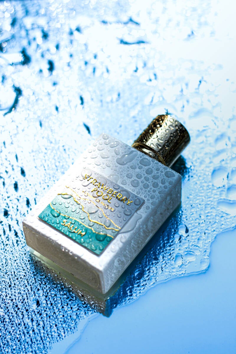 Bottle of Strawberry Pool extrait de parfum on watery blue background