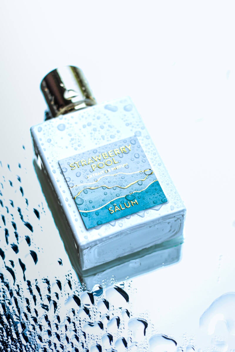 Minimalist photo of Strawberry Pool fragrance bottle with water texture