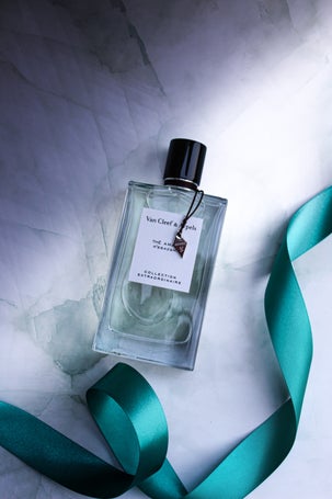 Bottle of Van Cleef & Arpels Thé Amara Eau de Parfum from the Collection Extraordinaire, placed on a marble background with a teal satin ribbon.