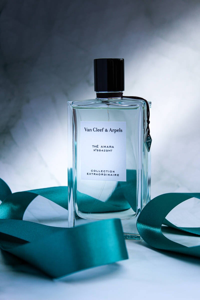 Thé Amara by Van Cleef & Arpels displayed on a soft marble background with a flowing teal ribbon.