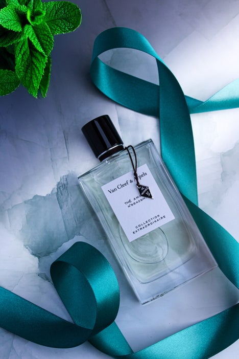 Bottle of Van Cleef & Arpels Thé Amara Eau de Parfum from the Collection Extraordinaire, placed on a marble background with a teal satin ribbon and mint leaves