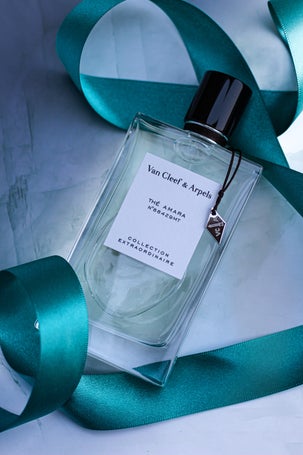 Bottle of Van Cleef & Arpels Thé Amara Eau de Parfum from the Collection Extraordinaire, placed on a marble background with a teal satin ribbon.