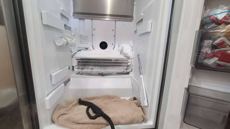 Appliance technician repairing a refrigerator in Burlington