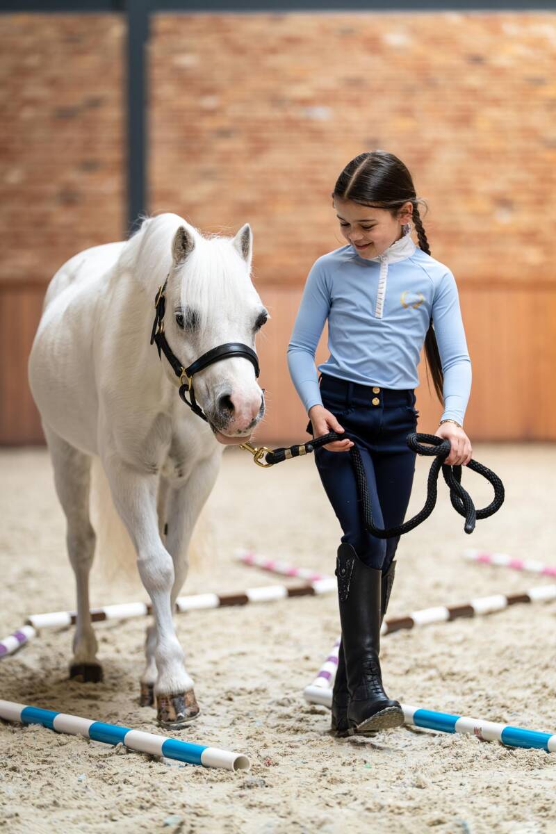 meisje loopt met pony tussen mini jump balken