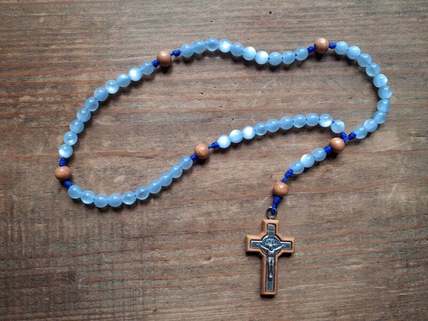 Rosario con grani di similmadreperla azzurri, filo blu e crocifisso di San Benedetto in legno d'olivo