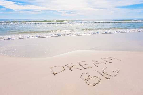 Bild: Meer und Sandstrand, im Sand stehten die Wörter Dream Big