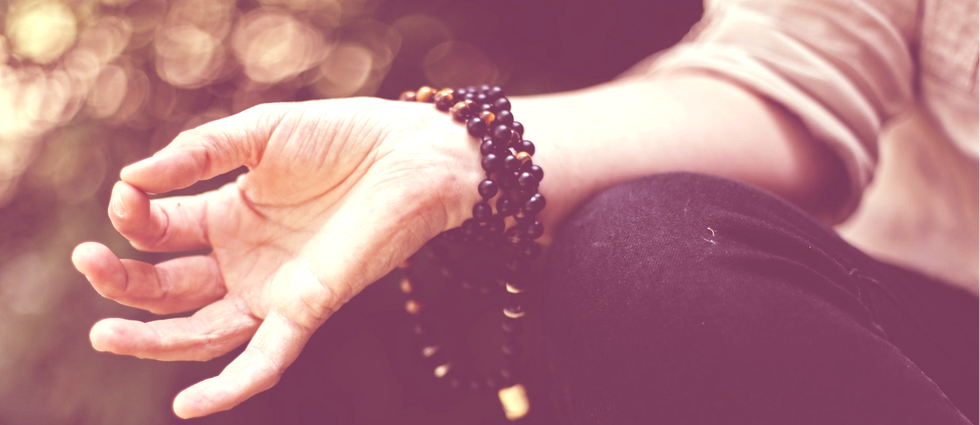 Main en Jnana mudra, dont le poignet est entouré d'un mala de perles foncées
