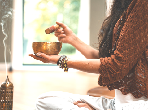 femme assise tenant un bol chantant entre les mains