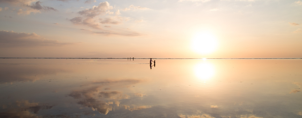 Mer calme, lisse comme un miroir qui reflete les nuages, avec 2 personnages au loin dans l'eau